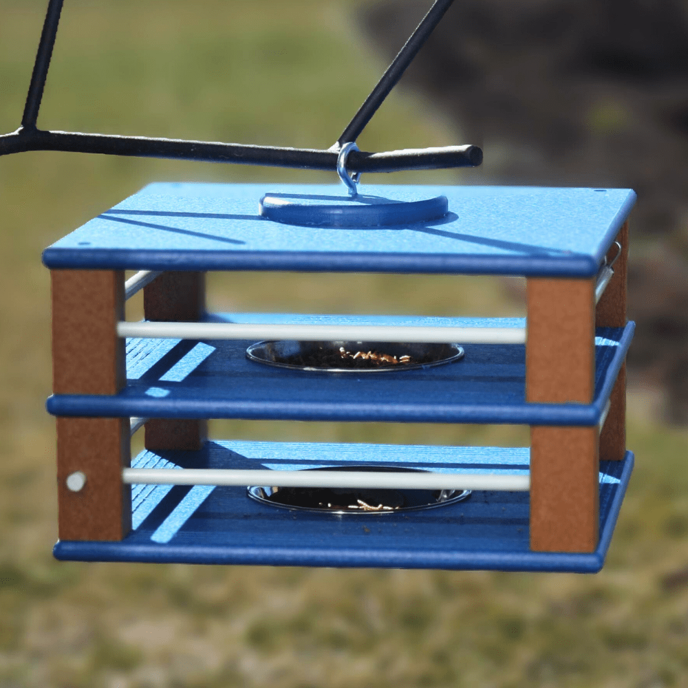 Dual Gilbertson Blue and brown bird feeder with three perches against a blurred natural background