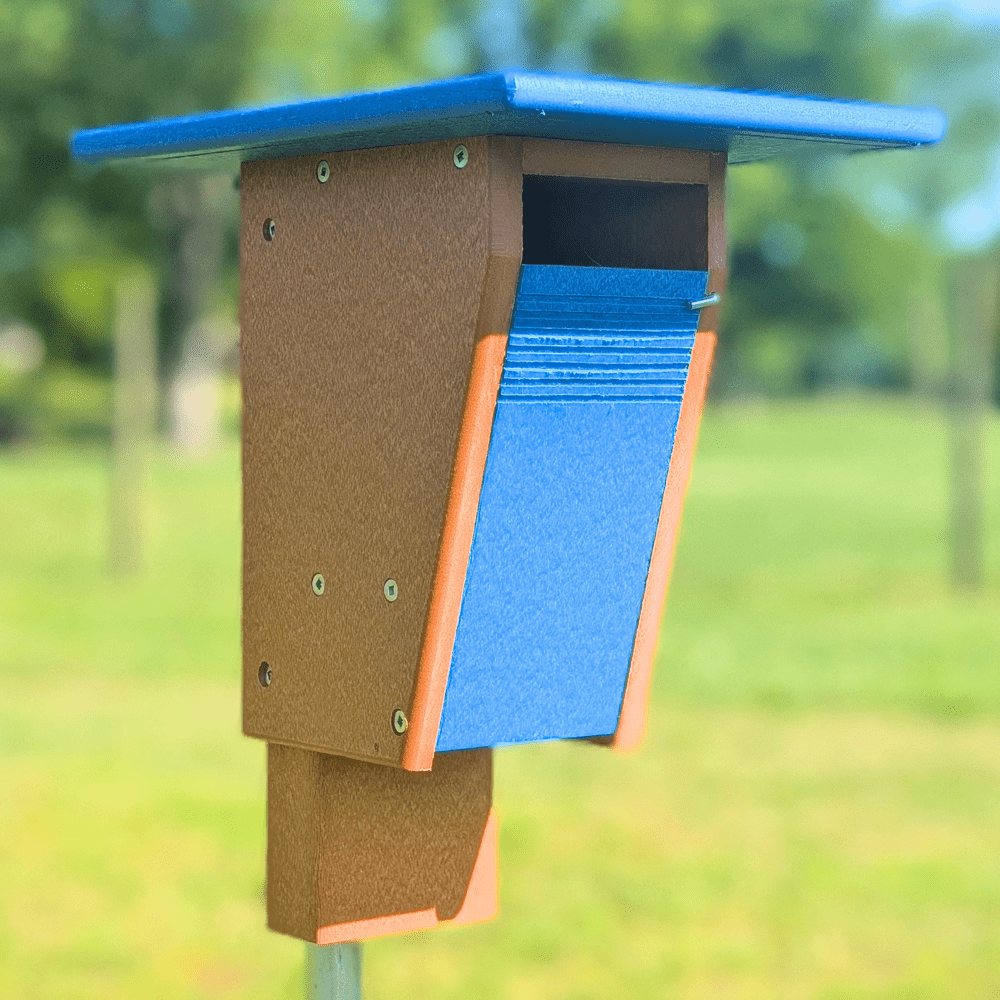 Birdhouse with blue roof and brown body on a blurred green background