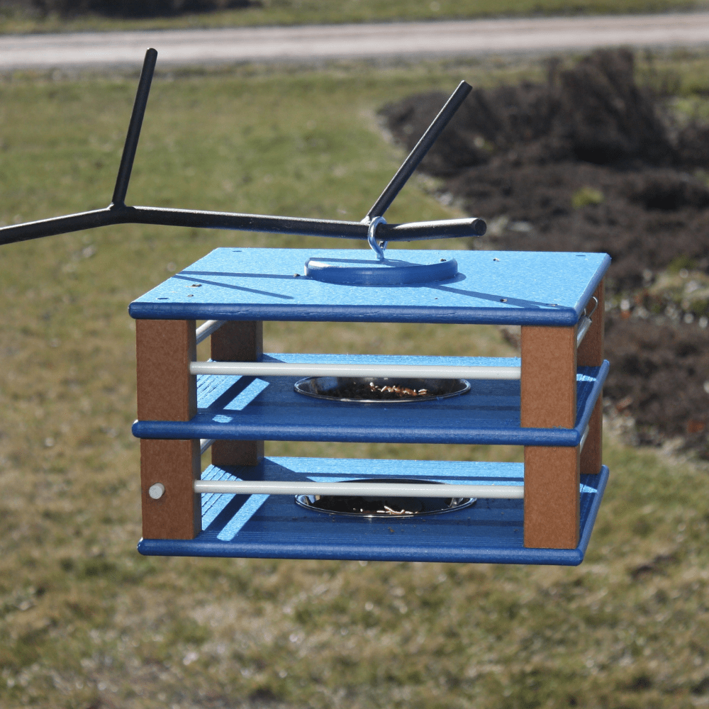 Dual Gilbertson Blue and brown bird feeder hanging outdoors on a grassy background