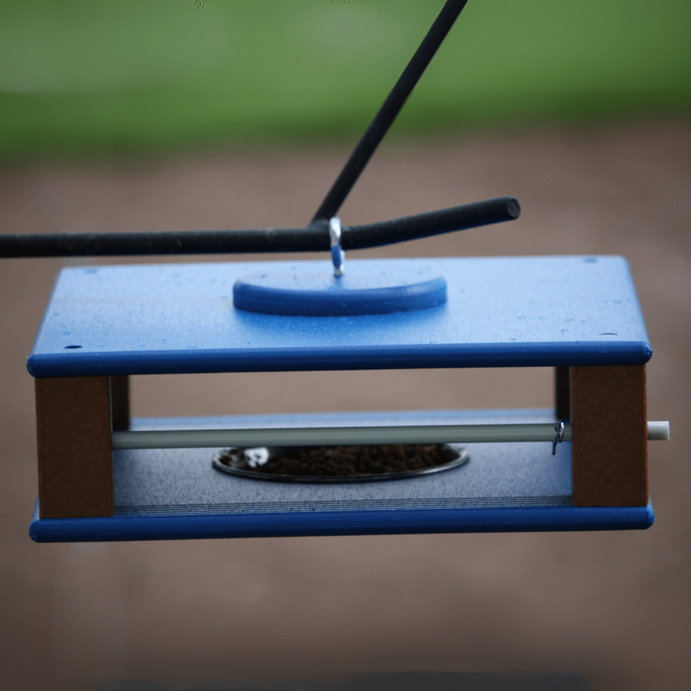 Gilbertson classic bird feeder hanging against a blurred green and brown background